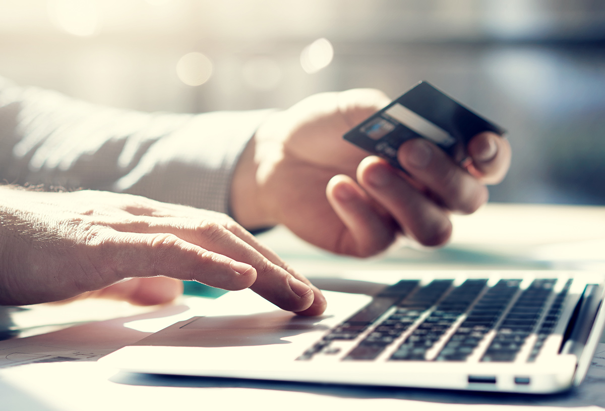 Closeup photo of a businessman working on a laptop making an online payment with a credit card