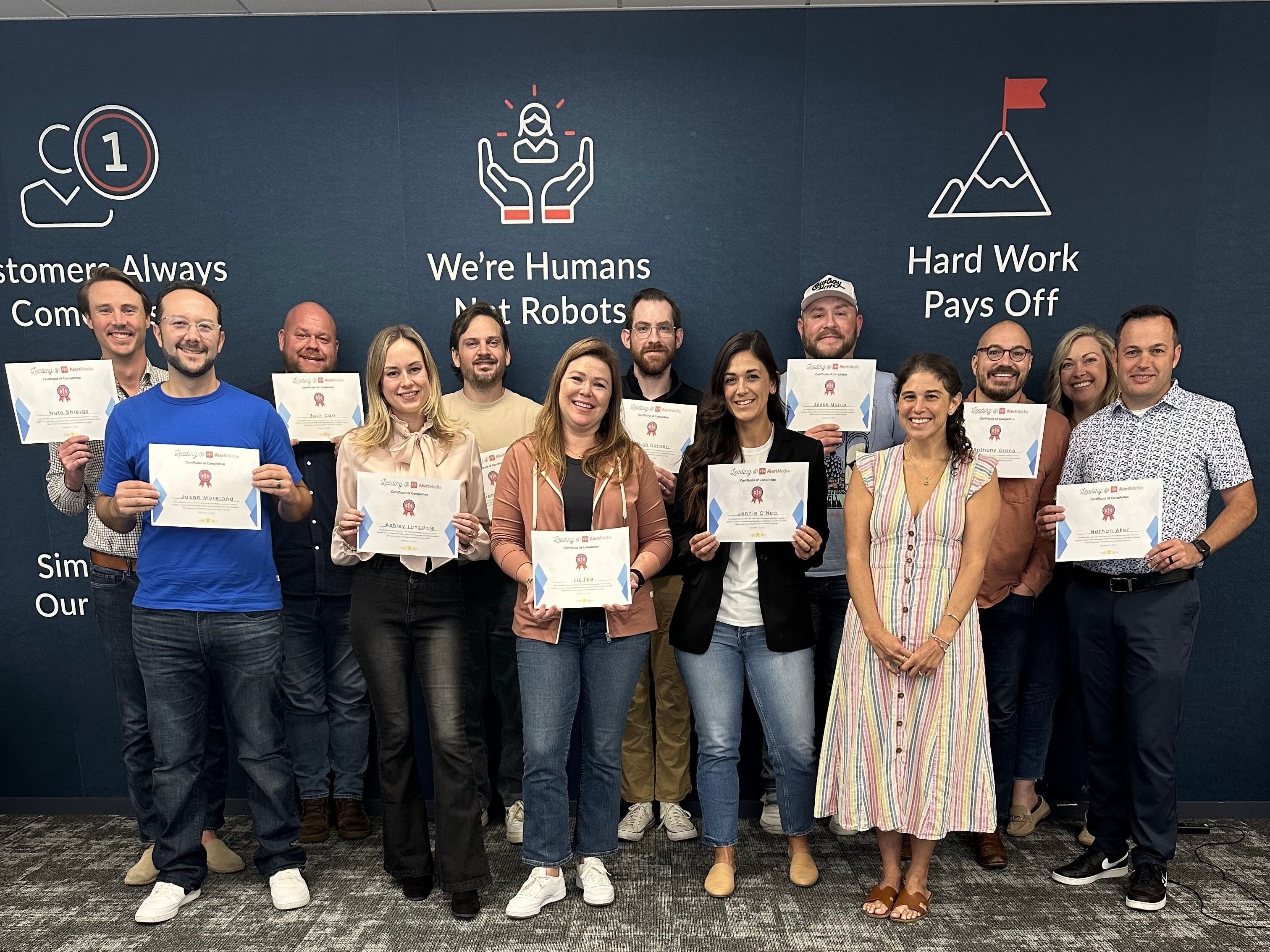 The AlertMedia team poses for a group photo holding certificates.