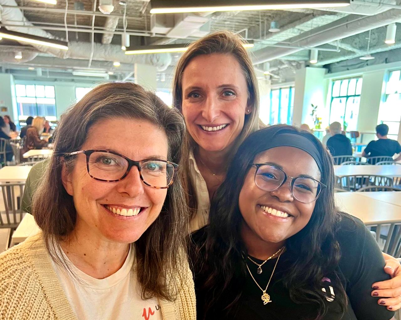 Three Udemy team members take a photo together in the office cafeteria.