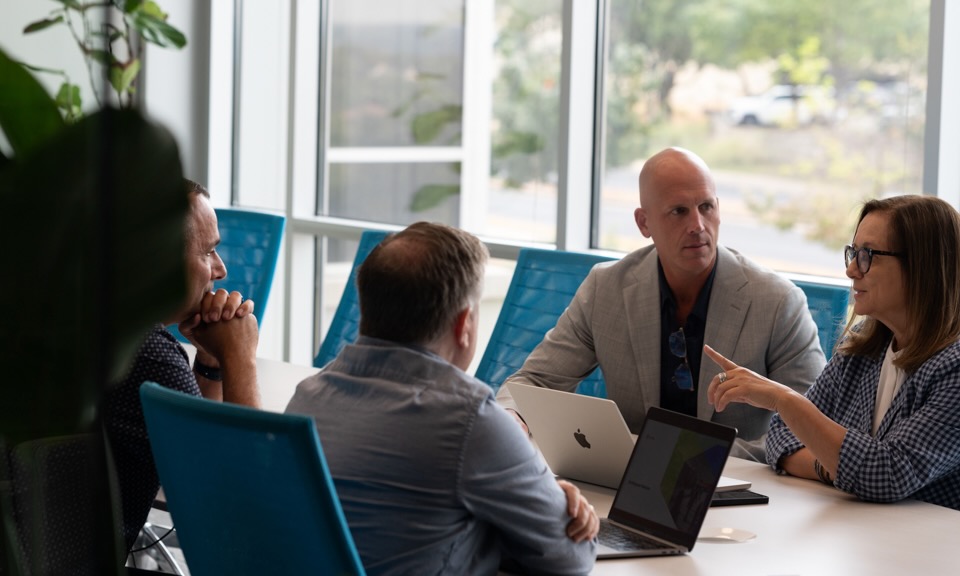 Four Brinqa leaders in discussion during a meeting.