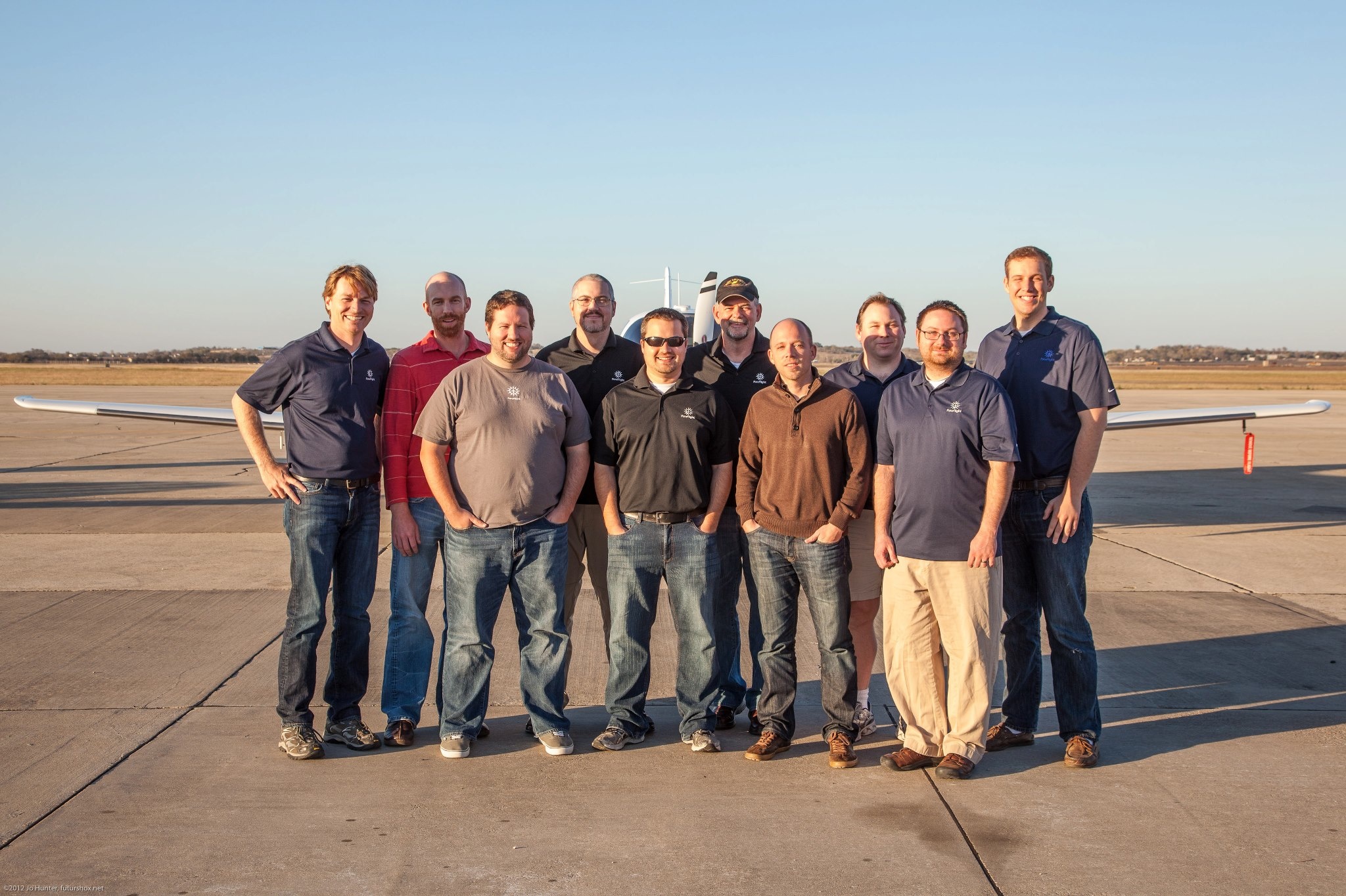 A group of ForeFlight employees stand in front of a small plane on a runway.