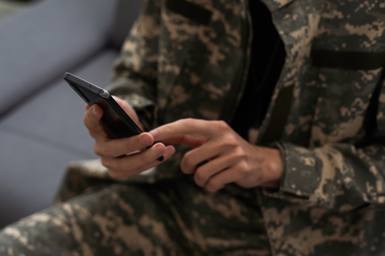 A person in army fatigues, holding a cellphone