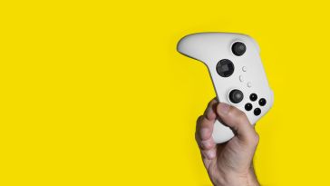 xbox controller in hand on yellow background